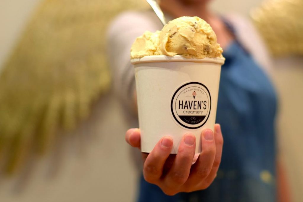 front view of woman holding havens creamery ice cream bowl with two scoops of vanilla inside