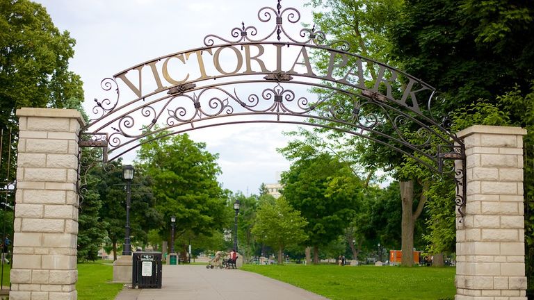 front view of victoria park metal banner entrance with pillars and view of park