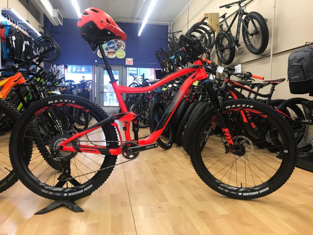 front view of red and black bike in a bike shop with wooden floor