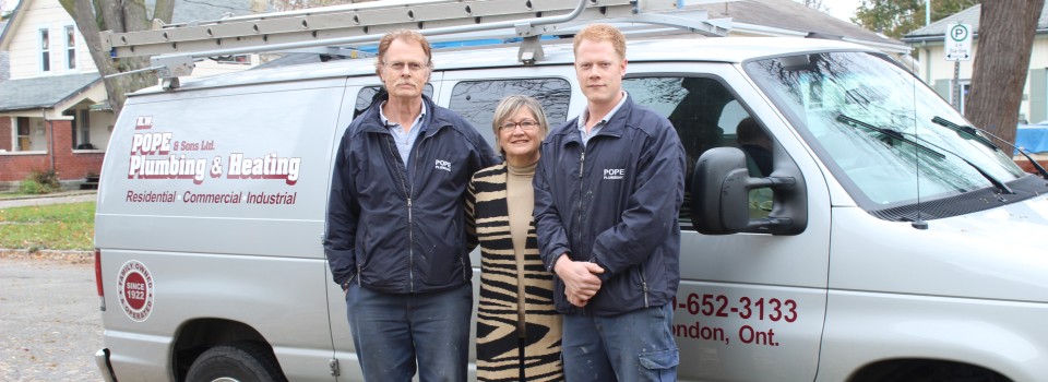 three people standing in front of work van posing and smiling at camera