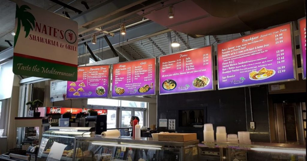 view of shawarma menu with red and purple lighting with four screens in front of service counter