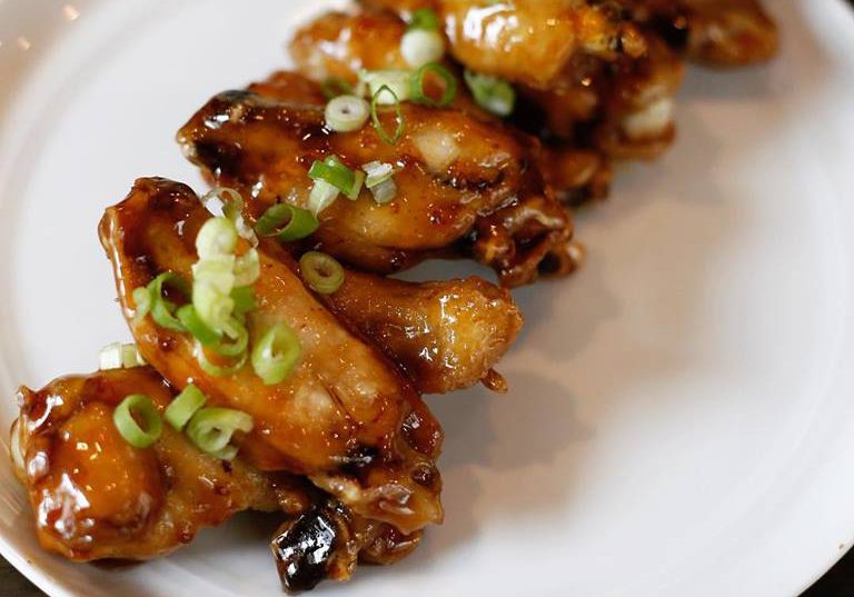 overhead shot of chicken wings with green onion garnish on a white plate
