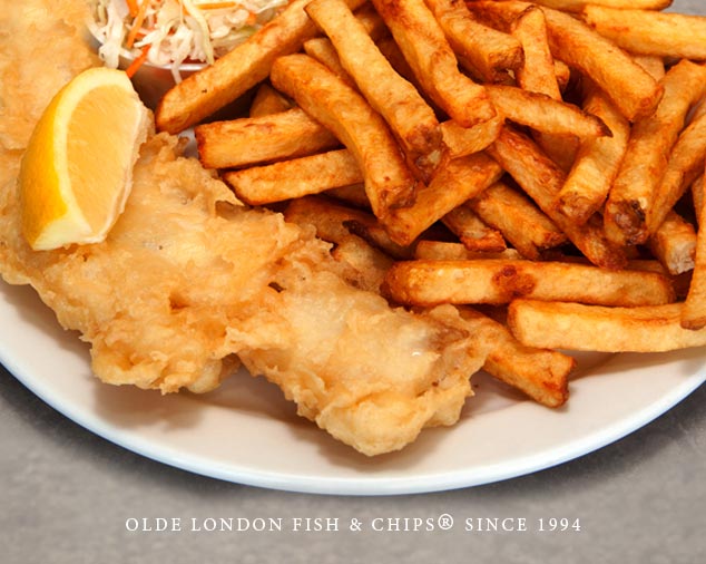 top view of battered fish and chip plate with lemon garnish on white plate