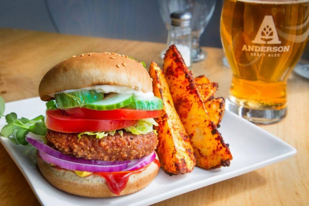 side view of crusted patty burger with garnish closed with wedges side on beer to the right hand side