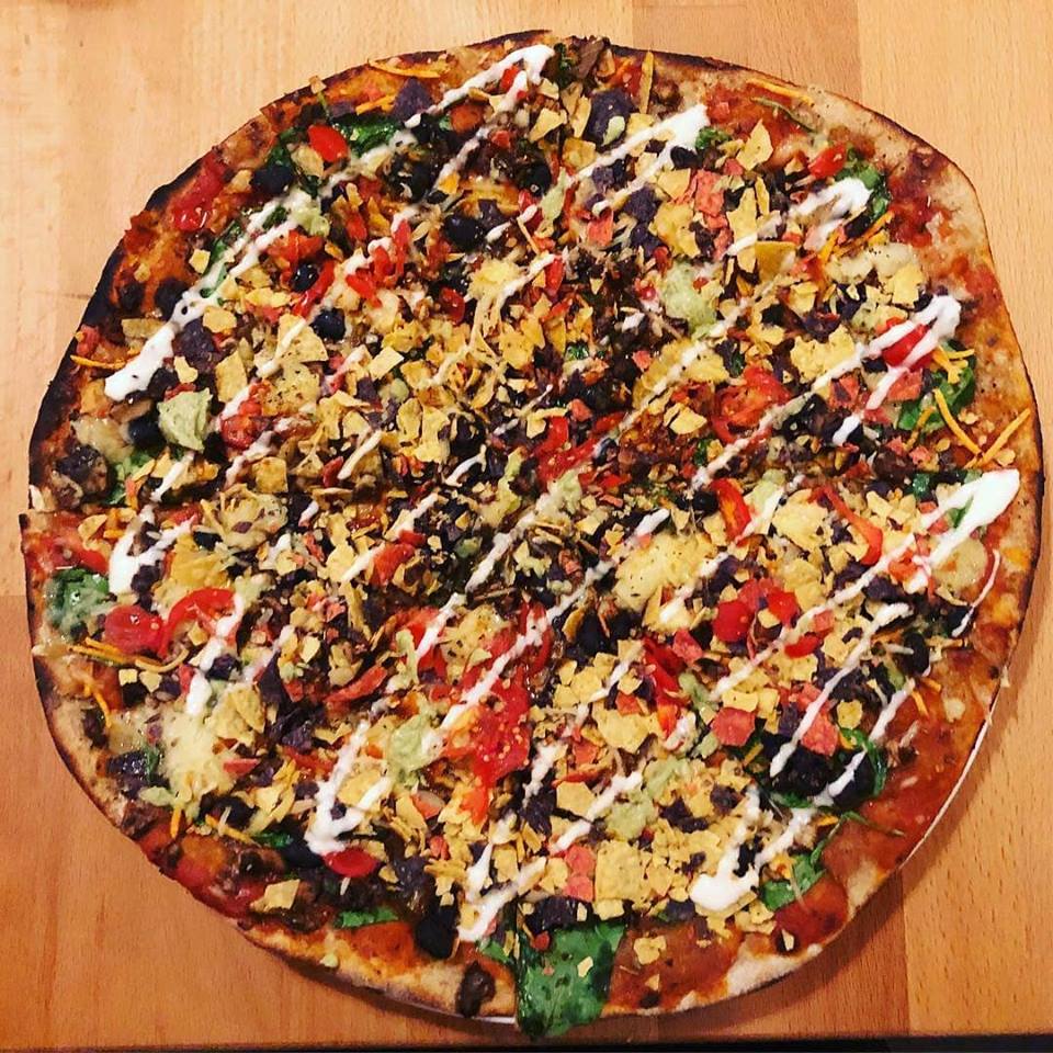 top view of deluxe pizza with white drizzle on top on wooden counter