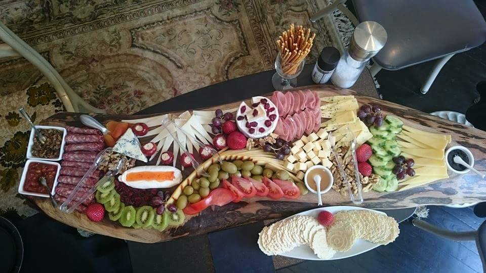 overview of a large charcuterie board with various meat cheese and vegetable selections and some crackers on the side