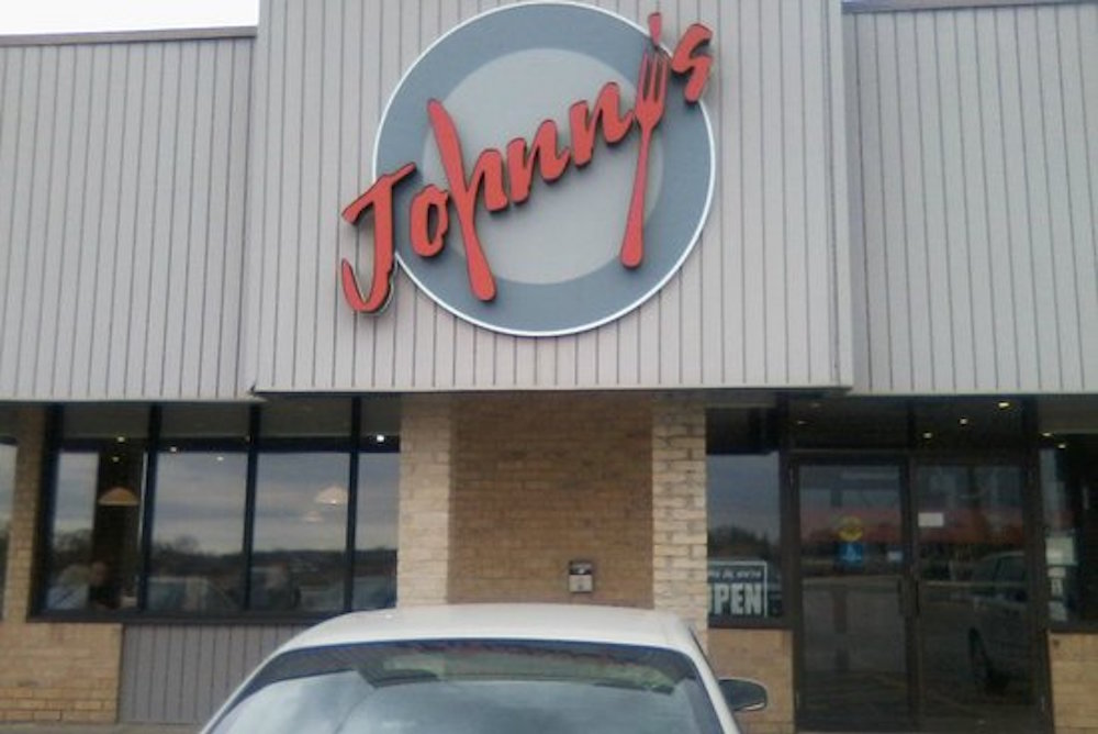 exterior of restaurant with red logo and car in front