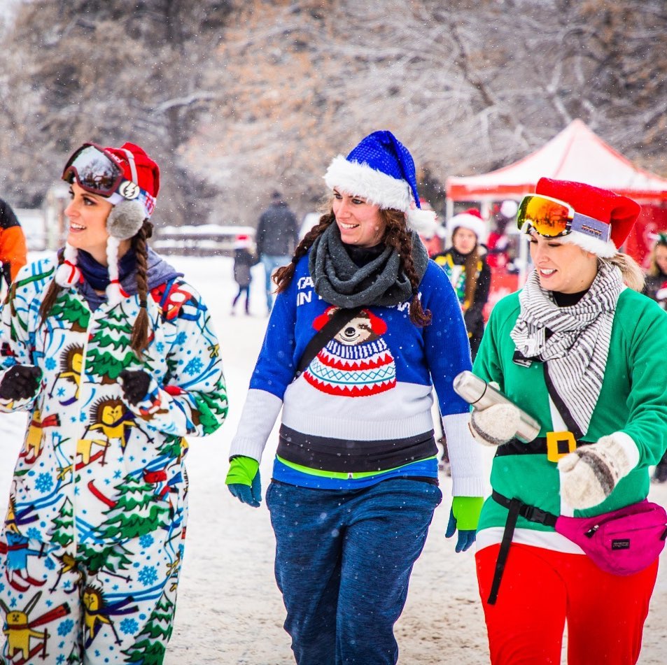 3 women in christmas sweaters and hats outside looking to the left of camera