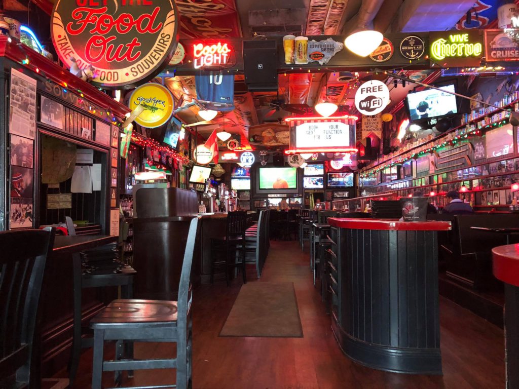 view of empty bar with many neon signs, seating and various rustic decor throughout and on the walls