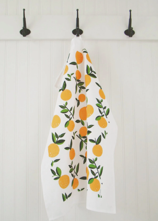 large kitchen tea towel with lemon print hanging on a black hook