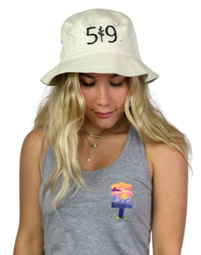 woman modelling a bucket hat in beige with branding on the front in black against a white background