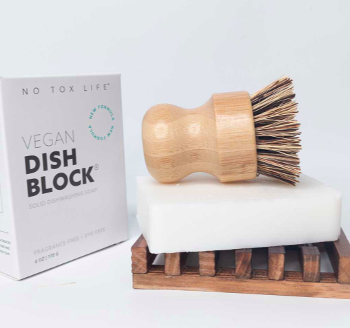 small bamboo dish scrubber sitting on top of a bar of soap sitting in a container with product box to the left