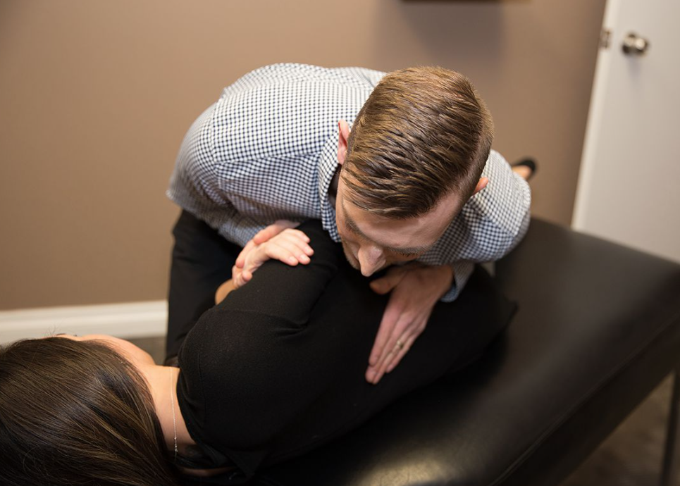man adjusting a woman who is laying on a massage table