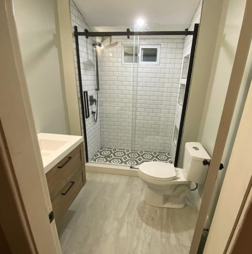 recently renovated bathroom with white and black styled shower and brown accents in the powder area
