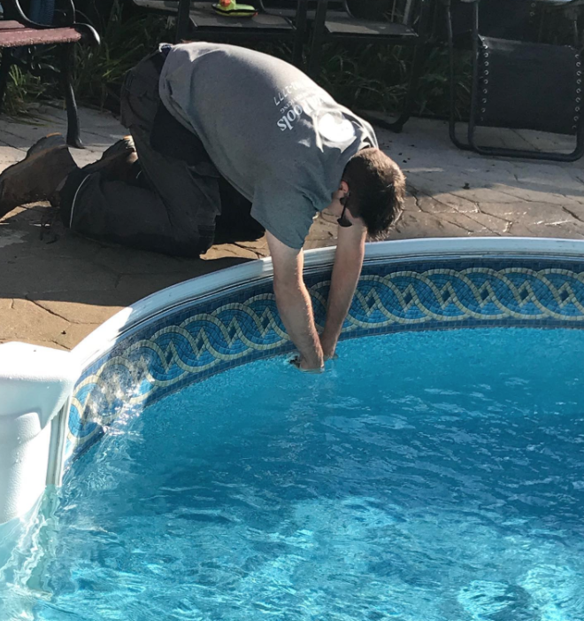 man with hands in a pool to fix it