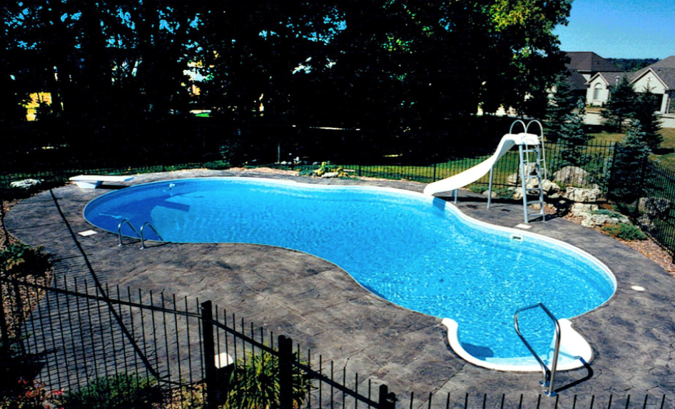 large round shaped pool with water slide and iron fence surrounding it