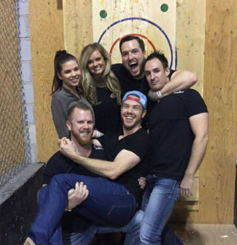group of people at an axe throwing facility smiling and having a good time