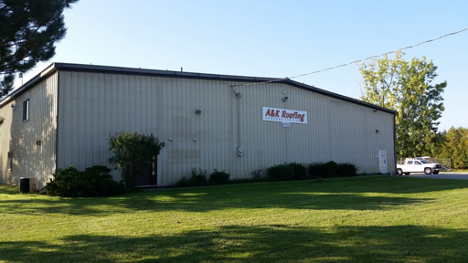 exterior of a large warehouse building with branding on the front and a large lawn in front
