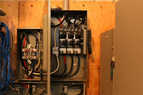 an open fuse box in a basement with many wires running throughout