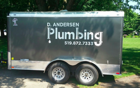 large grey plumbing trailer with company name on the side with a phone number