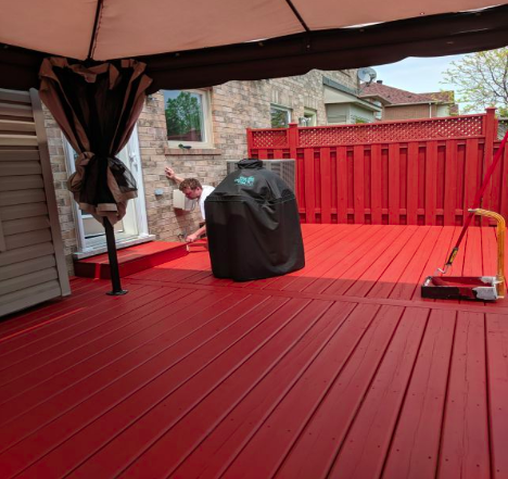 back deck being painted red with a barbecue sitting on top