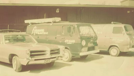 old style photo of work vans with ladders attached