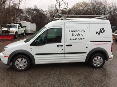picture of a small work van with company name and phone number on the side and a roof rack on top
