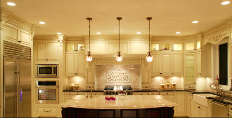 interior of a well lit and light kitchen with many pot lights and hanging lights over the island