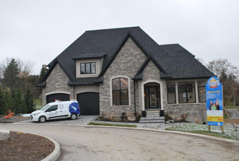 exterior of a large home with a work truck parked in the driveway on a cloudy day