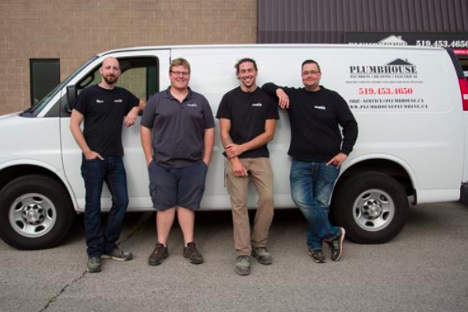four men smiling at the camera standing in front of a white work truck