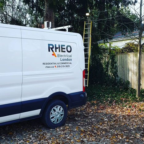 white work truck with company name and phone number on the side backed into a driveway with a ladder set up in the background