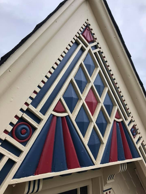 peak of a house that has been painted in blue red and beige inside the pattern that has been etched