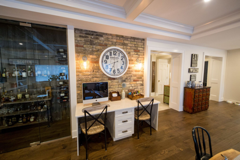 office area with exposed brick and hardwood floors with various pieces of furniture and wine cellar to the left
