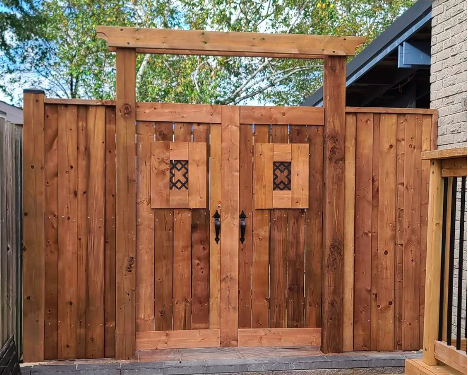 large wooden entrance to a backyard with dark finishes and archway at the top