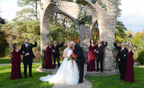 Wedding party under circular structure with bride and groom kissing