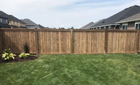 long wooden fence in a backyard with a flower bed to the left