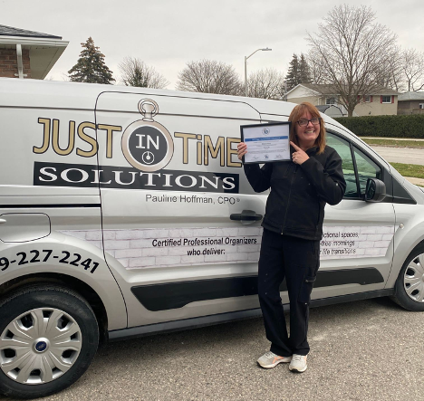 Woman holding certificate standing in front of a work truck smiling