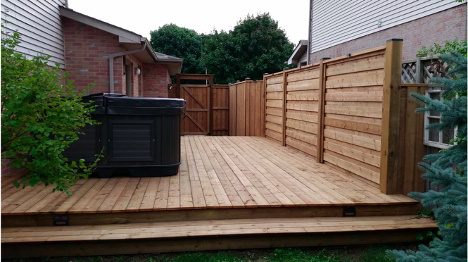 backyard deck with privacy wall to the right and hottub to the left