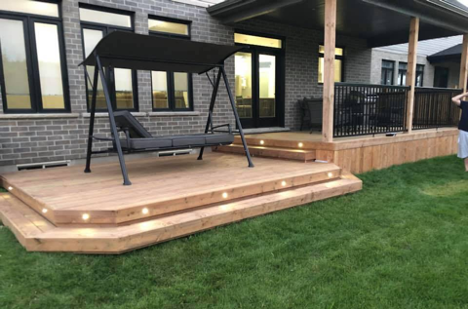 deck with iron railing featuring two step walk down to another deck level with porch swing on it