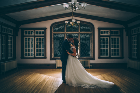 bride and groom kissing under a light in an empty room