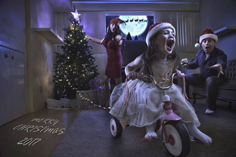 digital photo of family setting up christmas tree with young girl riding a tricycle with tree lights attached to wheel