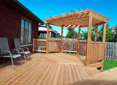 wooden deck feature with pergola covering circular area and patio chairs along the house