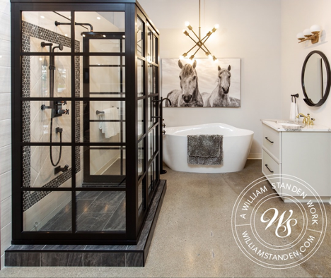 bathroom with large stand up shower with black paned glass with gold and dark detailing