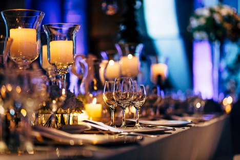 wedding table setup with candles, wine glasses, and dinerware with dim lighting