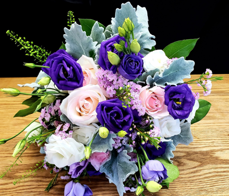 large carry flower bouquet with pink, purple and white flowers and greenery throughout
