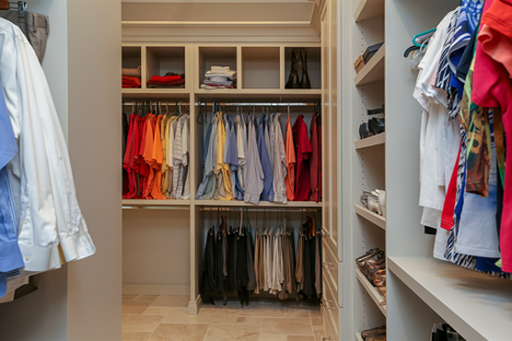 interior of a large walk in closet with organizers with many clothes hung folded and set away