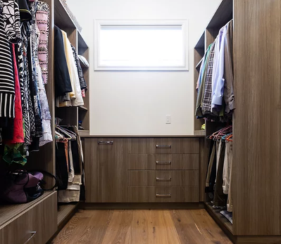 interior of large walk in closet with many things hung and cabinetry throughout