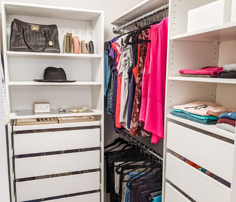 interior of walk in closet with organizer shelves with many things hung folded and put away