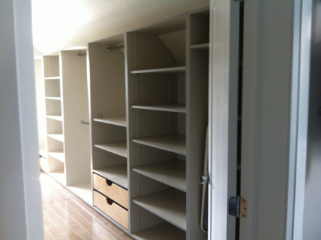 interior of an empty walk in closet with organizers and shelving