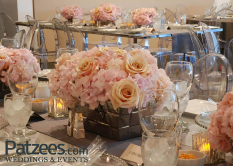 event setup with dining tables with large pink and peach flower bouquets as centerpieces with table set for dinner